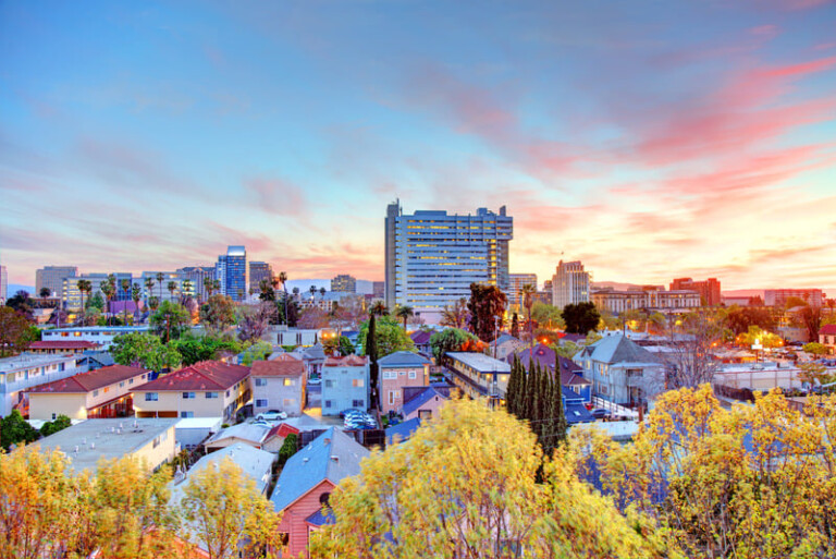 Foto: Impresionante vista de una ciudad al atardecer, con el Edificio Gouppers en el horizonte, rodeado de vibrantes colores y naturaleza urbana. Perfecto para reflejar innovación y energía positiva.